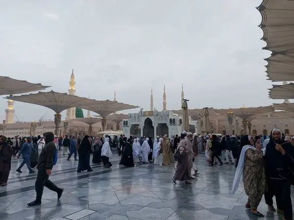Al-Madinah al-Munawwarah, Suudi Arabistan - 27 Şubat 2025: Medine 'de Peygamberin Camii açık şemsiyeler ve minarelerle bulutlu bir gökyüzü altında, İslami mimariyi gözler önüne seren.