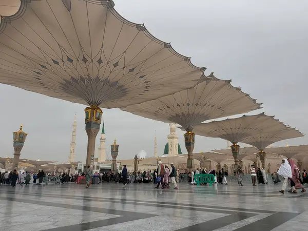 Al-Madinah al-Munawwarah, Suudi Arabistan - 27 Şubat 2025: Medine 'de Peygamberin Camii açık şemsiyeler ve minarelerle bulutlu bir gökyüzü altında, İslami mimariyi gözler önüne seren.