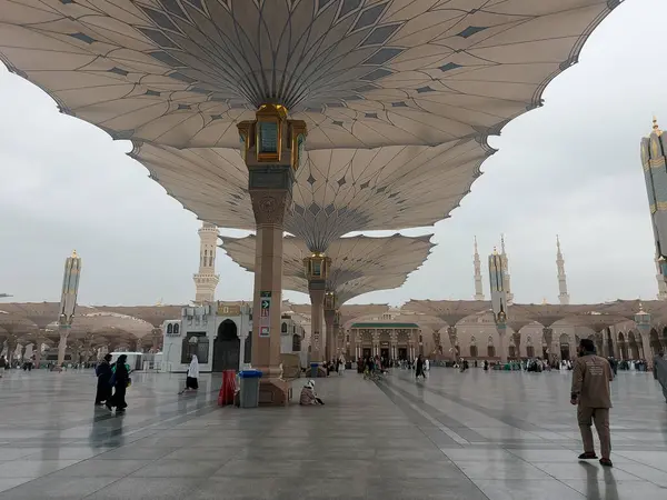 Al-Madinah al-Munawwarah, Suudi Arabistan - 27 Şubat 2025: Medine 'de Peygamberin Camii açık şemsiyeler ve minarelerle bulutlu bir gökyüzü altında, İslami mimariyi gözler önüne seren.