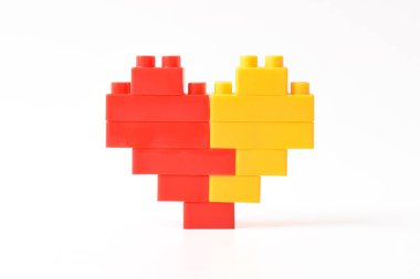 Oyuncak blokların kalbi beyaz arka planda izole edilmiş, üst görüntü kesilmiş. Plastik yapı taşları