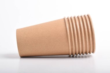 Beyaz arkaplanda izole edilmiş kahverengi kullan-at bardakların yığını.