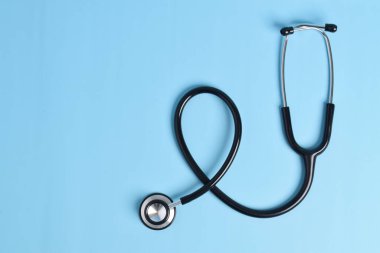 Açık mavi arkaplanda steteskop izole edildi, fotokopi alanı metni ile birlikte. Kardiyoloji kavramı