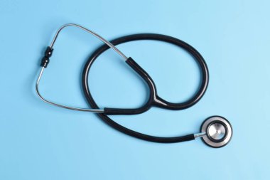 Açık mavi arka planda siyah steteskop izole edilmiş. düz yatış, üst görünüm