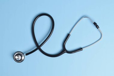Açık mavi arka planda siyah steteskop izole edilmiş. düz yatış, üst görünüm