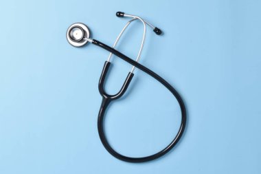 Stetoskop açık mavi arka planda, üst görüntüde izole edilmiş. Tıbbi araç