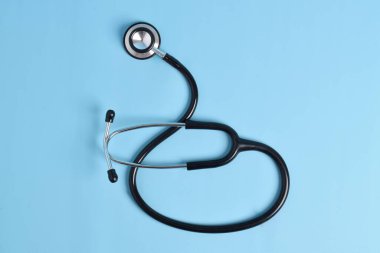 Stetoskop açık mavi arka planda, üst görüntüde izole edilmiş. Tıbbi araç