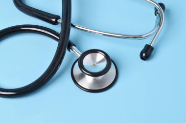 Açık mavi arka planda steteskop, yakın plan. Metin için boşluk