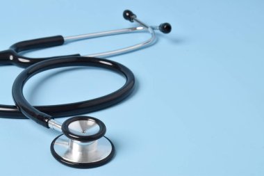 Açık mavi arka planda steteskop, yakın plan. Metin için boşluk