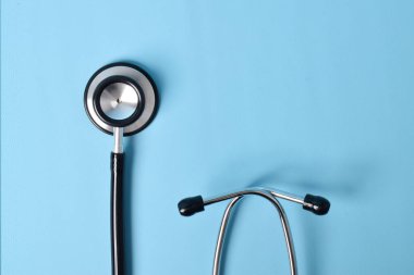 Açık mavi arka planda steteskop, üst manzara, yakın çekim. Metin için boşluk