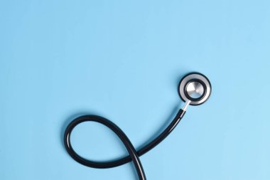 Açık mavi arka planda steteskop, üst manzara, yakın çekim. Metin için boşluk