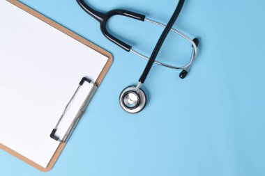 Açık mavi arkaplanda steteskop bulunan boş bir tıbbi dosya. Boşluğu kopyala.
