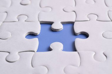 Mavi arkaplanda eksik parçalı beyaz bulmaca, yakın plan