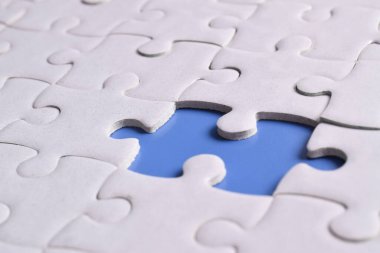 Mavi arkaplanda eksik parçalı beyaz bulmaca, yakın plan