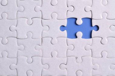 Mavi arkaplanda eksik parçalı beyaz bulmaca, yakın plan