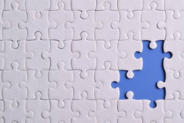 Mavi arkaplanda eksik parçalı beyaz bulmaca, yakın plan