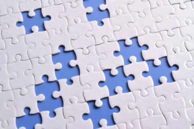 Mavi arkaplanda eksik parçalı beyaz bulmaca, üst görünüm