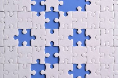 Mavi arkaplanda eksik parçalı beyaz bulmaca, üst görünüm