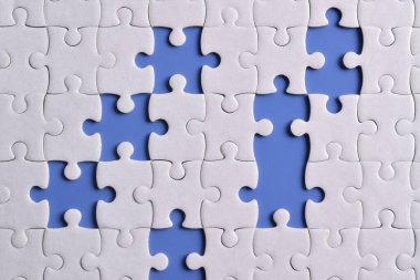 Mavi arkaplanda eksik parçalı beyaz bulmaca, üst görünüm