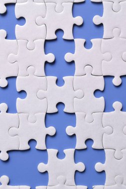 Mavi arkaplanda eksik parçalı beyaz bulmaca, üst görünüm
