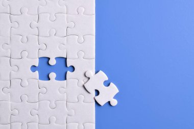 Mavi arka planda beyaz yapboz parçaları. Düz yatıyordu. Üst görünüm