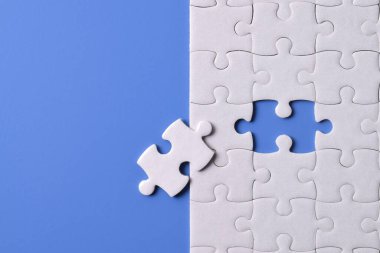 Mavi arka planda beyaz yapboz parçaları. Düz yatıyordu. Üst görünüm