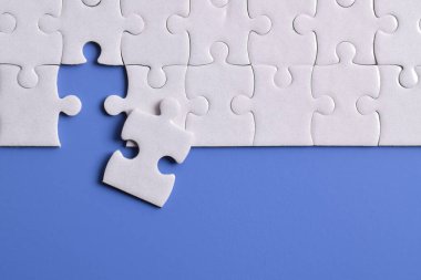 Mavi arka planda beyaz yapboz parçaları. Düz yatıyordu. Üst görünüm