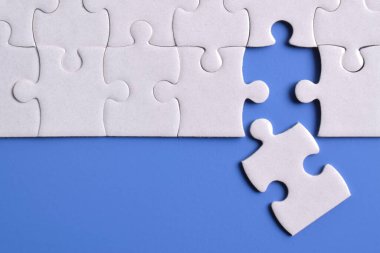 Mavi arka planda beyaz yapboz parçaları. Düz yatıyordu. Üst görünüm