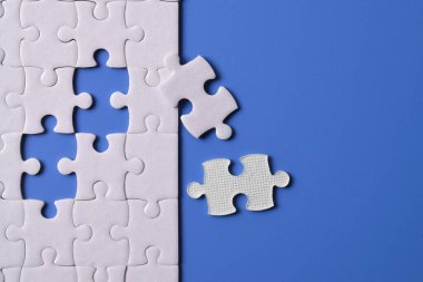 Mavi arka planı eksik olan beyaz bulmaca. Düz yatıyordu. Üst görünüm