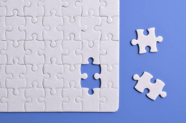 Mavi arka planı eksik olan beyaz bulmaca. Düz yatıyordu. Üst görünüm