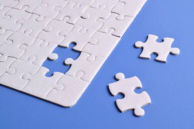 Mavi arka planı eksik olan beyaz bulmaca. Düz yatıyordu. Üst görünüm