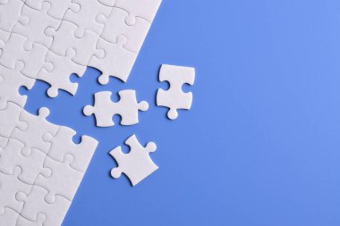 Mavi arka planı eksik olan beyaz bulmaca. Düz yatıyordu. Üst görünüm