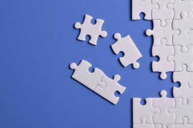 Mavi arka planı eksik olan beyaz bulmaca. Düz yatıyordu. Üst görünüm