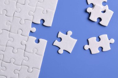 Mavi arka planı eksik olan beyaz bulmaca. Düz yatıyordu. Üst görünüm