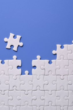 Mavi arka planda beyaz yapboz parçaları. Düz yatıyordu. Üst görünüm