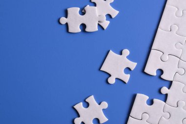 Mavi arka planda beyaz yapboz parçaları. Düz yatıyordu. Üst görünüm