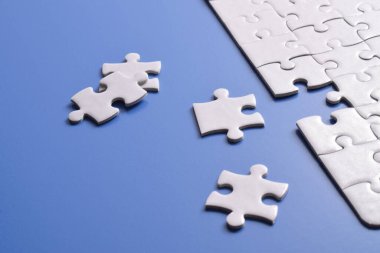 Mavi arka planı eksik olan beyaz bulmaca. Düz yatıyordu. Üst görünüm