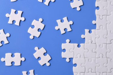 Mavi arka planda beyaz yapboz parçaları. Düz yatıyordu. Üst görünüm