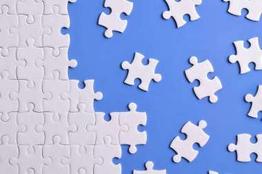 Mavi arka planda beyaz yapboz parçaları. Düz yatıyordu. Üst görünüm