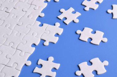 Mavi arka planda beyaz yapboz parçaları. Düz yatıyordu. Üst görünüm