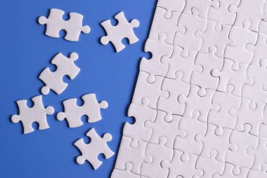 Mavi arka planda beyaz yapboz parçaları. Düz yatıyordu. Üst görünüm