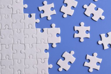 Mavi arka planda beyaz yapboz parçaları. Düz yatıyordu. Üst görünüm