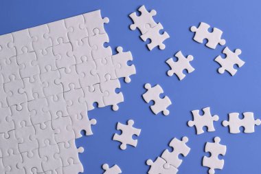 Mavi arka planda beyaz yapboz parçaları. Düz yatıyordu. Üst görünüm