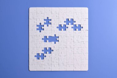 Mavi arka planda beyaz yapboz parçaları. Beyaz kare yapboz parçaları ızgarası. İş geçmişi. Metin için boşluk kopyala, üst görünüm.