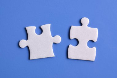 Mavi arka planda iki beyaz yapboz parçası. Üst görünüm