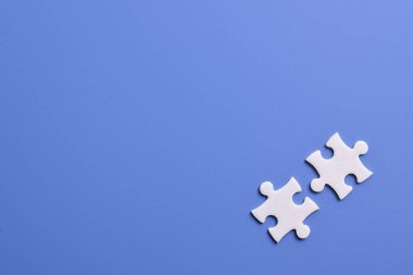 Mavi arka planda iki beyaz yapboz parçası. Metin için boşluk kopyala, üst görünüm.