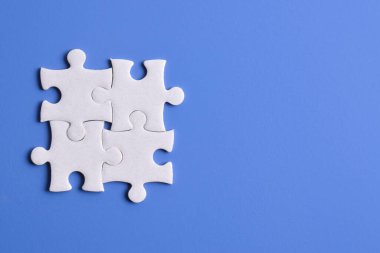 Mavi arka planda dört yapboz parçası. Takım çalışmasında doğru çözümleri bulma kavramı.