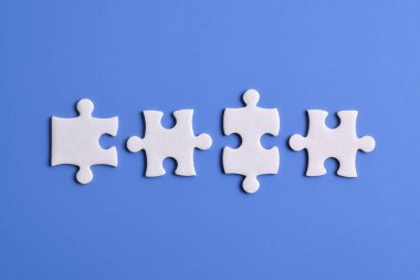 Mavi arka planda dört yapboz parçası. Takım çalışmasında doğru çözümleri bulma kavramı.