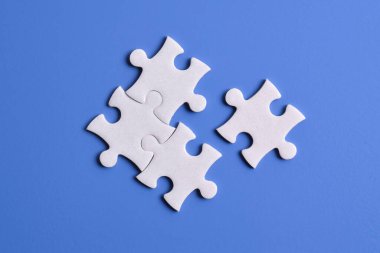 Mavi arka planda dört yapboz parçası. Takım çalışmasında doğru çözümleri bulma kavramı.