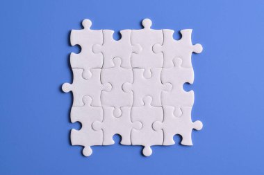 Mavi arka planda beyaz yapboz parçaları, üst manzara. Metin için boşluk