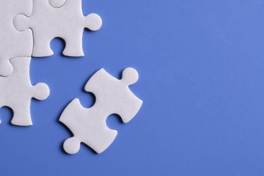 Mavi arka planda beyaz yapboz parçaları. Düz yatıyordu. Üst görünüm